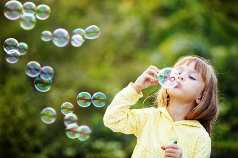 Summer fun for kids playing outdoors blowing bubbles